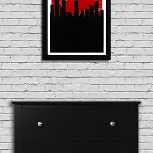 May include: A framed art print featuring the Denver skyline in black against a red background. The text "DENVER" and "THE MILE HIGH CITY" are displayed in white. The print hangs above a black dresser with silver knobs.