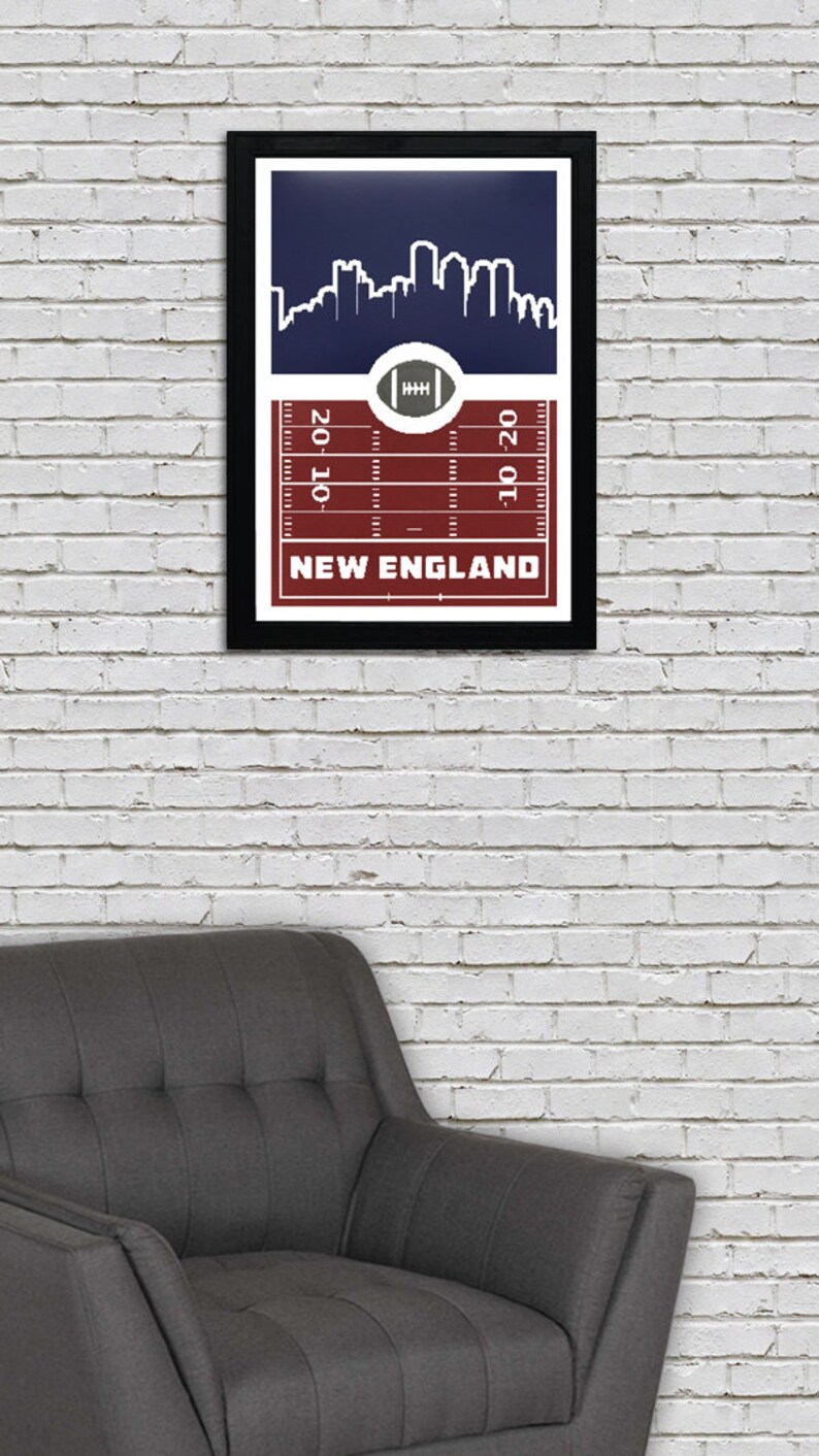 May include: A framed print with a navy blue background featuring a white silhouette of a city skyline. The bottom of the print has a red and white football field design with the text "NEW ENGLAND" and yard lines marked "20", "10", and "10".