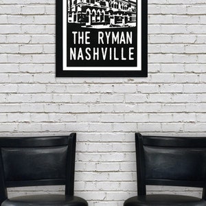 May include: Black and white illustration of the Ryman Auditorium in Nashville, Tennessee. The building is depicted with a red and white sunburst behind it. The text "The Ryman Nashville" is printed below the building.