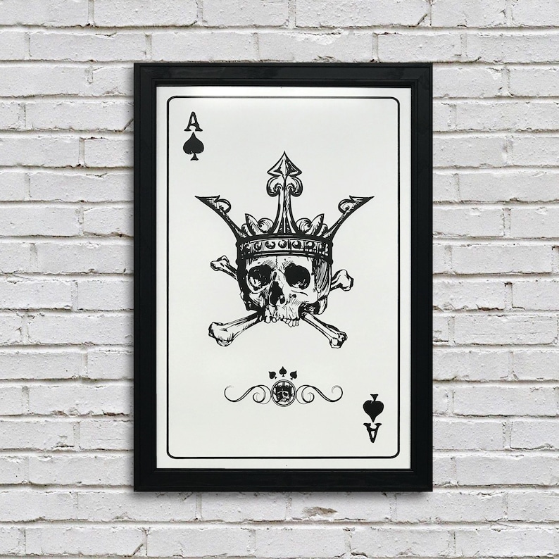 May include: A black and white illustration of a playing card, the Ace of Spades. The card features a skull wearing a crown and crossed bones. The card is framed in a black frame.