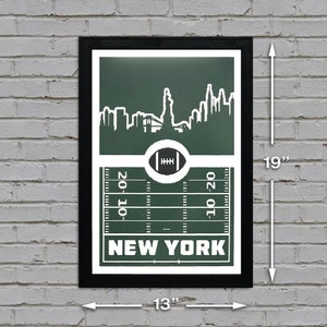 Puede incluir: Una impresi&oacute;n enmarcada en verde y blanco con un marco negro. La impresi&oacute;n presenta un horizonte estilizado de la ciudad de Nueva York con la Estatua de la Libertad en el centro. El horizonte est&aacute; sobre un campo de f&uacute;tbol verde con l&iacute;neas de yarda blancas y el texto "NEW YORK" en la parte inferior. La impresi&oacute;n mide 13 pulgadas de ancho por 19 pulgadas de alto.