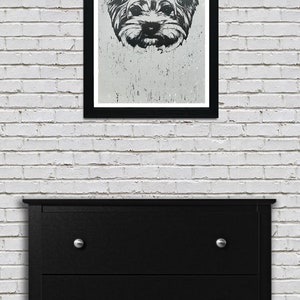 May include: Black and white illustration of a Yorkshire Terrier dog's face in a black frame on a white brick wall.