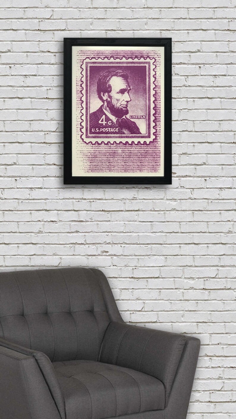 May include: A framed print of a vintage US postage stamp featuring a portrait of Abraham Lincoln. The stamp is purple and white and says "4&cent; U.S. POSTAGE" and "LINCOLN".