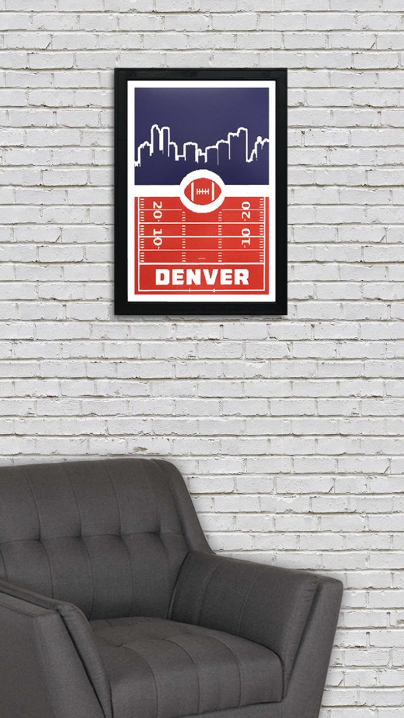 May include: A framed print with a red and white football field design. The print features a skyline of Denver, Colorado, and the text "DENVER" at the bottom.