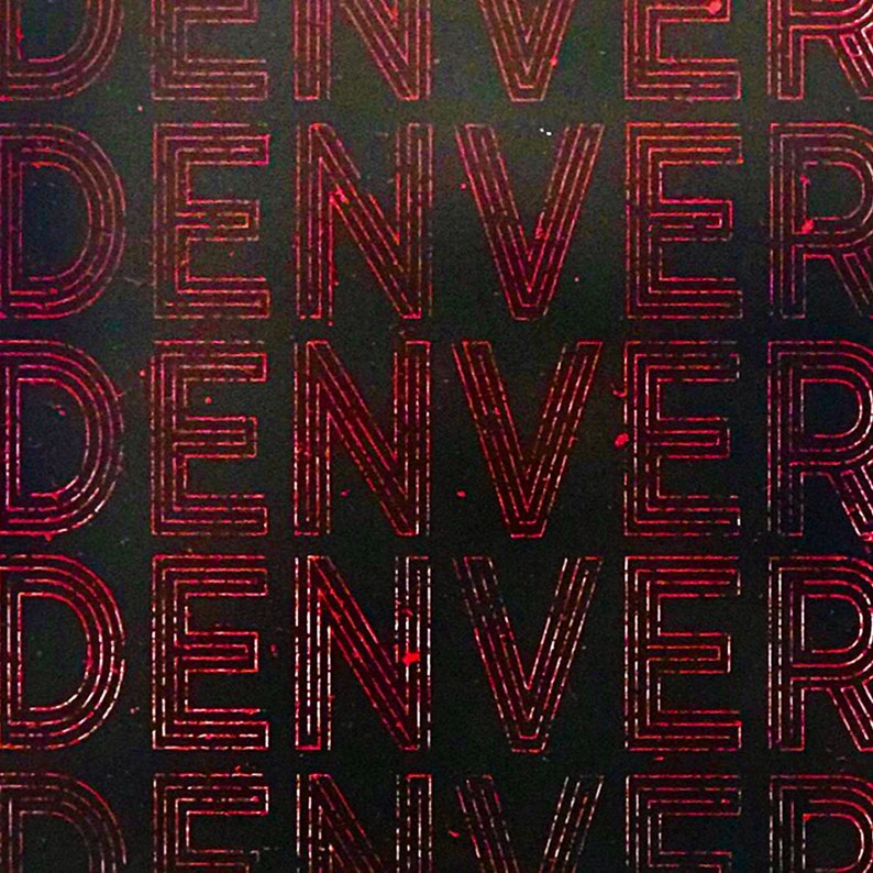 May include: A close-up of a black background with the word "DENVER" repeated multiple times in a red, outlined font.