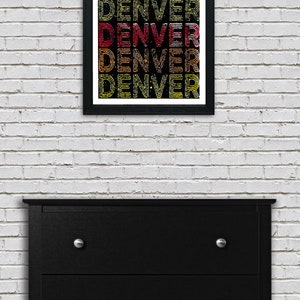 May include: A framed print with the word "DENVER" repeated five times in a retro style font. The letters are outlined in black and filled with a gradient of red, orange, and yellow. The background is black.