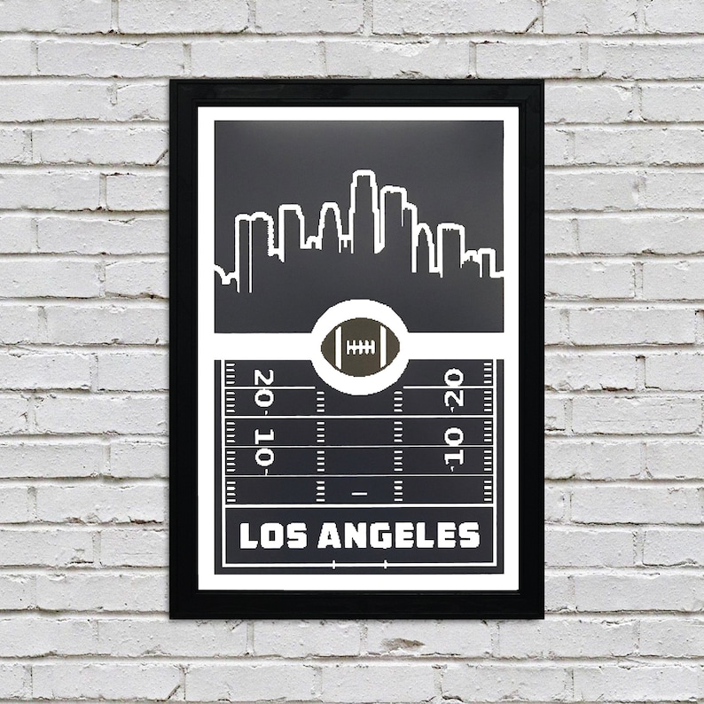 May include: Black and white print of the Los Angeles skyline with a football field and football in the center. The text "Los Angeles" is at the bottom of the print.