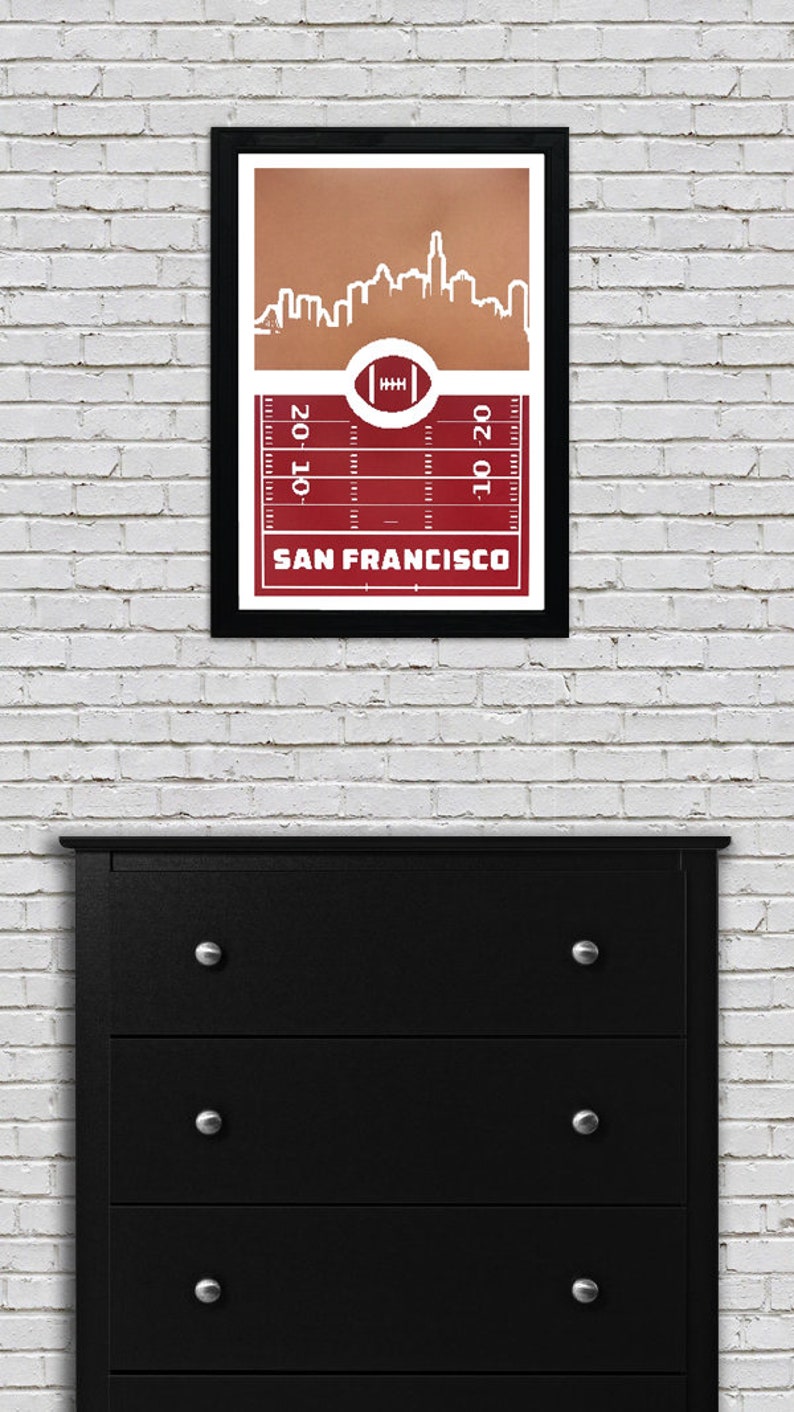 May include: A framed print of a red and white football field with a white outline of the San Francisco skyline. The text "SAN FRANCISCO" is printed below the field.