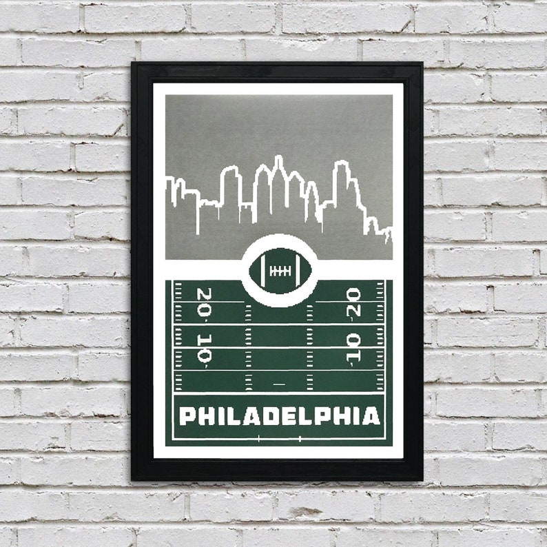 May include: A green and gray print featuring a stylized cityscape of Philadelphia, Pennsylvania, with a football field and a football in the center. The text "PHILADELPHIA" is printed below the field.