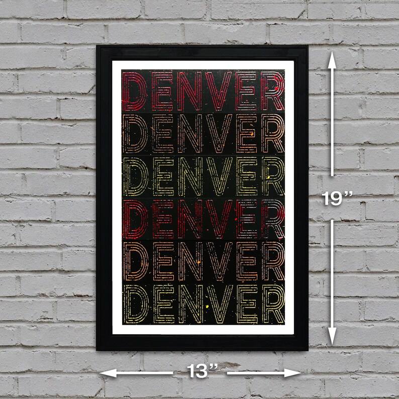 May include: A black framed print with the word "DENVER" repeated six times in a gradient of red, orange, and yellow on a black background. The print measures 13 inches wide by 19 inches tall.