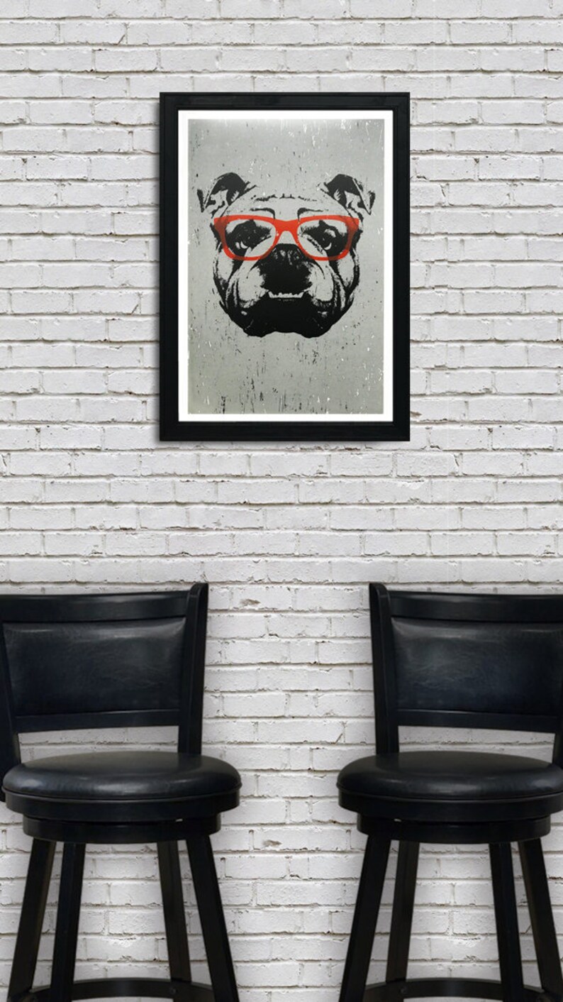 May include: A black and white illustration of a bulldog wearing red glasses, framed in a black frame and hanging on a white brick wall. Two black bar stools are in the foreground.