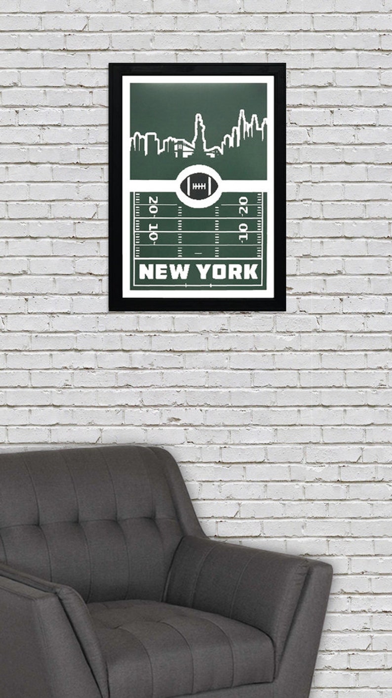 Puede incluir: Una impresi&oacute;n enmarcada con un fondo verde que presenta una silueta blanca del horizonte de la ciudad de Nueva York. El horizonte se coloca sobre un campo de f&uacute;tbol con l&iacute;neas de yarda y el texto "NEW YORK" debajo.
