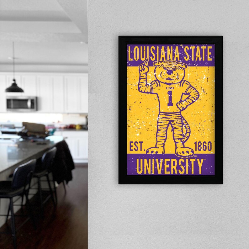 May include: A framed print displaying the Louisiana State University mascot, a tiger in a number 1 jersey. The print has a distressed, vintage style with the words "LOUISIANA STATE UNIVERSITY" and "EST. 1860". The colour scheme is purple and gold.