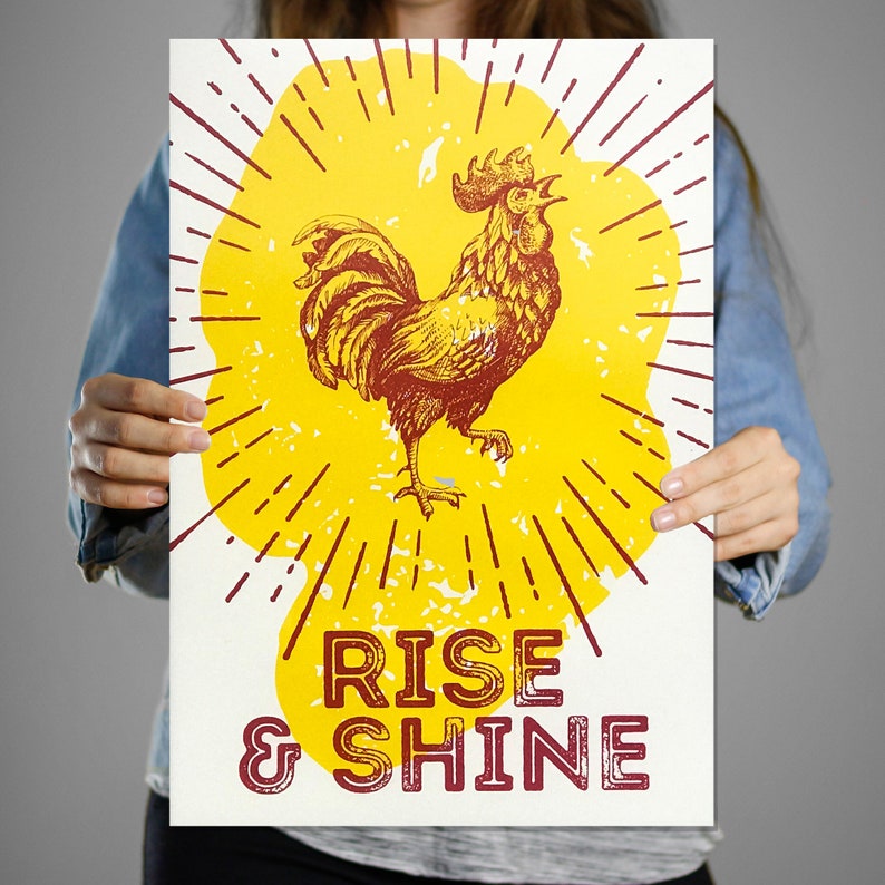 May include: A yellow and red poster with a rooster illustration and the text "Rise & Shine".