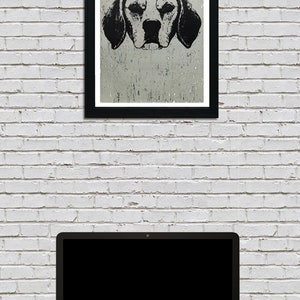 May include: Black and white illustration of a dog's head, printed on textured paper, framed in a black frame. The image is hanging on a white brick wall above a laptop computer.