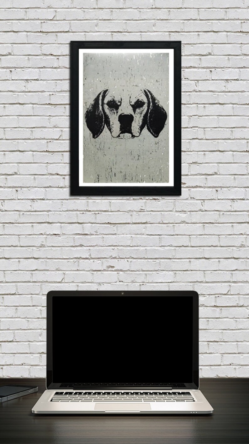 May include: Black and white illustration of a dog's head, printed on textured paper, framed in a black frame. The image is hanging on a white brick wall above a laptop computer.