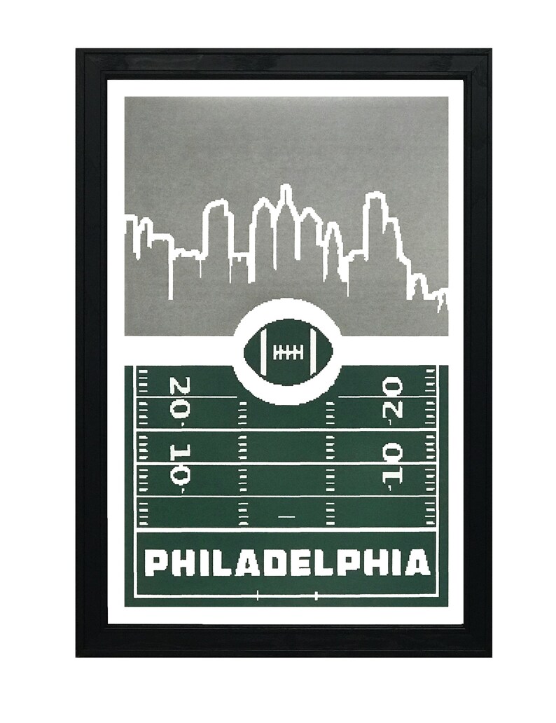 May include: A framed print with a silver cityscape silhouette of Philadelphia, a green football field with yard lines, and the word "PHILADELPHIA" in white text.