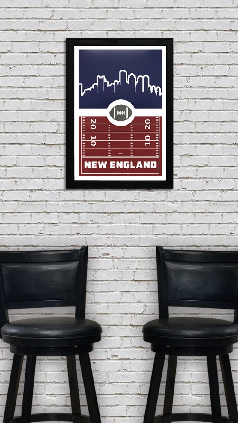 May include: A framed print with a navy blue background featuring a white silhouette of a city skyline. The bottom of the print has a red and white football field design with the text "NEW ENGLAND" and yard lines marked "20", "10", and "10-20".