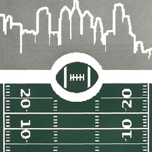 May include: A green and white football field with a white outline of a football in the center. The top of the image shows a white silhouette of a city skyline.