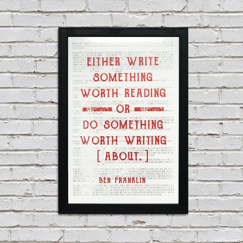 May include: A framed print with a white background and red text. The text reads "EITHER WRITE SOMETHING WORTH READING OR DO SOMETHING WORTH WRITING ABOUT." The quote is attributed to "BEN FRANKLIN".