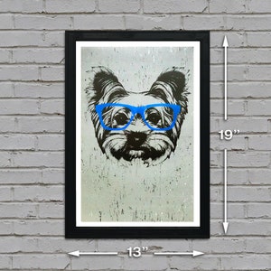 May include: A black and white illustration of a dog wearing blue glasses. The dog is a Yorkshire Terrier. The image is printed on a textured background and framed in a black frame. The frame is 13 inches wide and 19 inches tall.
