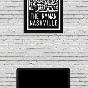 May include: Black and white illustration of the Ryman Auditorium in Nashville, Tennessee. The building is depicted with a red and white sunburst behind it. The text "THE RYMAN NASHVILLE" is below the building.