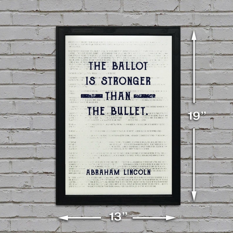 May include: A black framed print with a white background and blue text. The text reads "The ballot is stronger than the bullet. Abraham Lincoln". The print measures 13 inches wide and 19 inches tall.