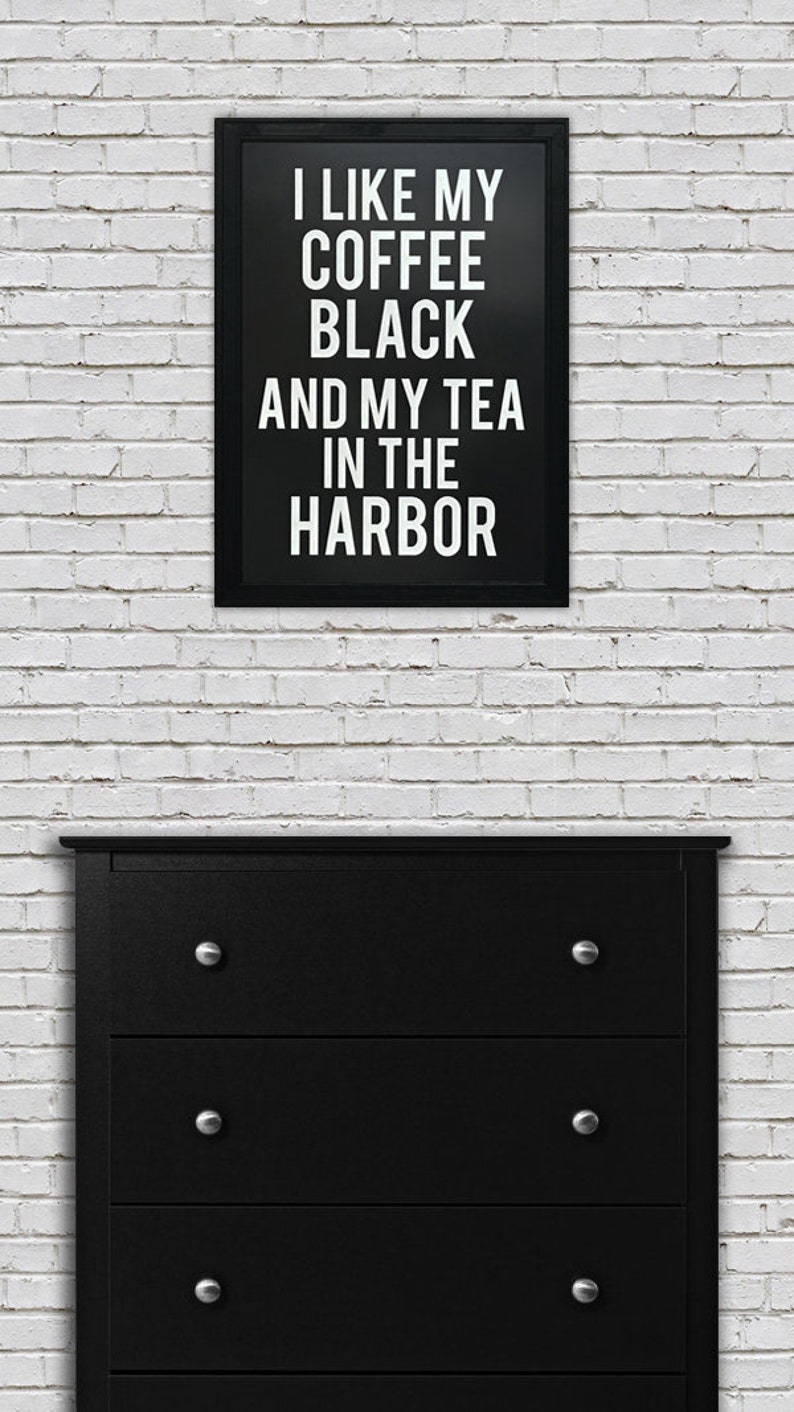 May include: Black and white framed print with the text "I like my coffee black and my tea in the harbor". The print is hanging on a white brick wall above a black dresser with four drawers.
