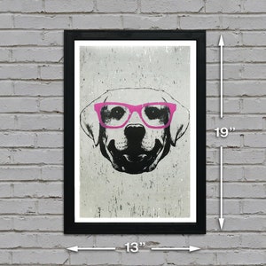 May include: A black and white illustration of a dog wearing pink glasses. The image is printed on a textured background and framed in a black frame. The frame measures 13 inches wide by 19 inches tall.