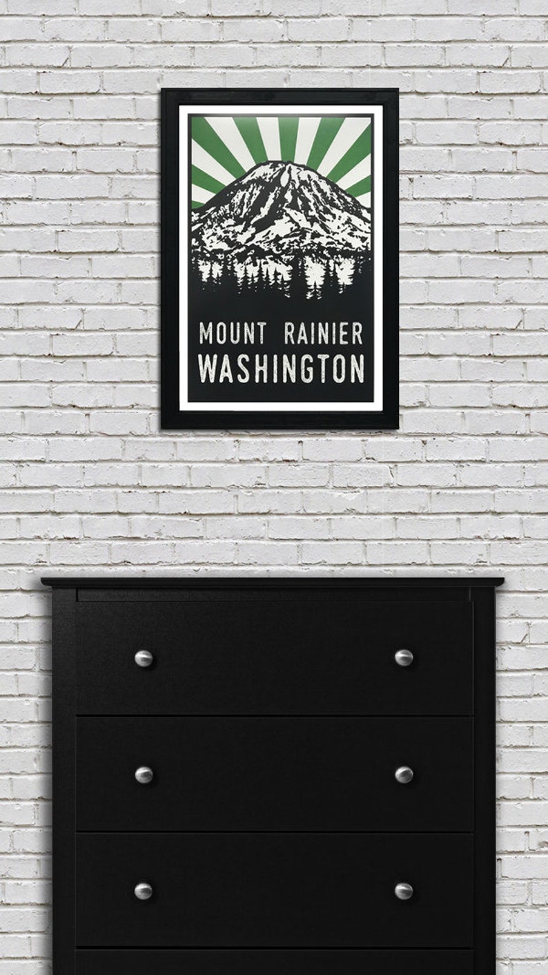 May include: A black framed poster with a green and white illustration of Mount Rainier in Washington state. The text "MOUNT RAINIER WASHINGTON" is printed in white below the illustration.