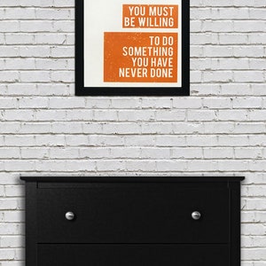 May include: Black framed motivational poster with white text on a white background. The text reads "If you want something you have never had you must be willing to do something you have never done."