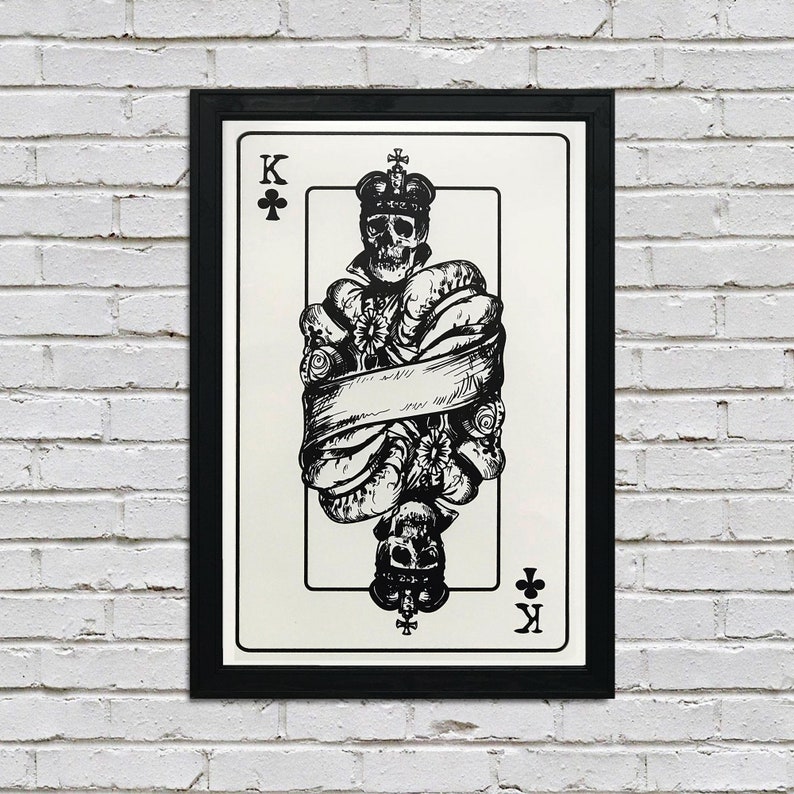 May include: A black and white illustration of the King of Clubs playing card. The King is depicted as a skull wearing a crown and surrounded by flowers and a banner.