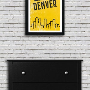Puede incluir: Un p&oacute;ster amarillo y negro con una pelota de baloncesto y la palabra "DENVER" en texto negro. El p&oacute;ster tambi&eacute;n presenta una silueta negra del horizonte de Denver.