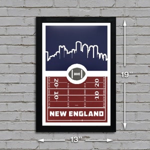 May include: A framed print of a football field with a skyline of New England in the background. The print is 13 inches wide and 19 inches tall. The field is red and white, with the words "NEW ENGLAND" printed in white at the bottom.