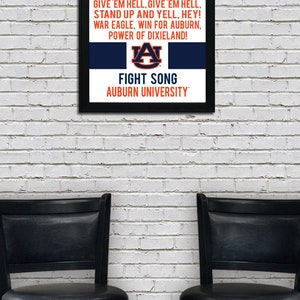 K&ouml;nnte beinhalten: Ein gerahmter Druck des Kampfliedtextes der Auburn University. Der Text ist in schwarzer Schrift auf blauem Hintergrund mit einem orange-blauen Logo der Auburn University. Der Rahmen ist schwarz.