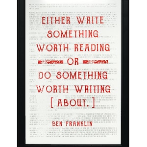 May include: A black framed print with a white background and red text. The text reads "Either write something worth reading or do something worth writing about." The quote is attributed to Ben Franklin.