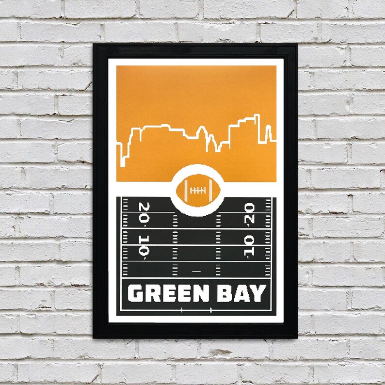 May include: A black framed print with a yellow background and a white silhouette of the Green Bay, Wisconsin skyline. The bottom of the print features a black and white football field with the words "Green Bay" in white.