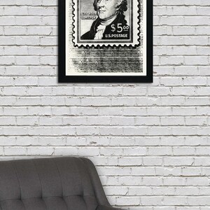 May include: Black and white framed print of a vintage postage stamp featuring a portrait of Alexander Hamilton with the text "ALEXANDER HAMILTON $5.00 U.S. POSTAGE".