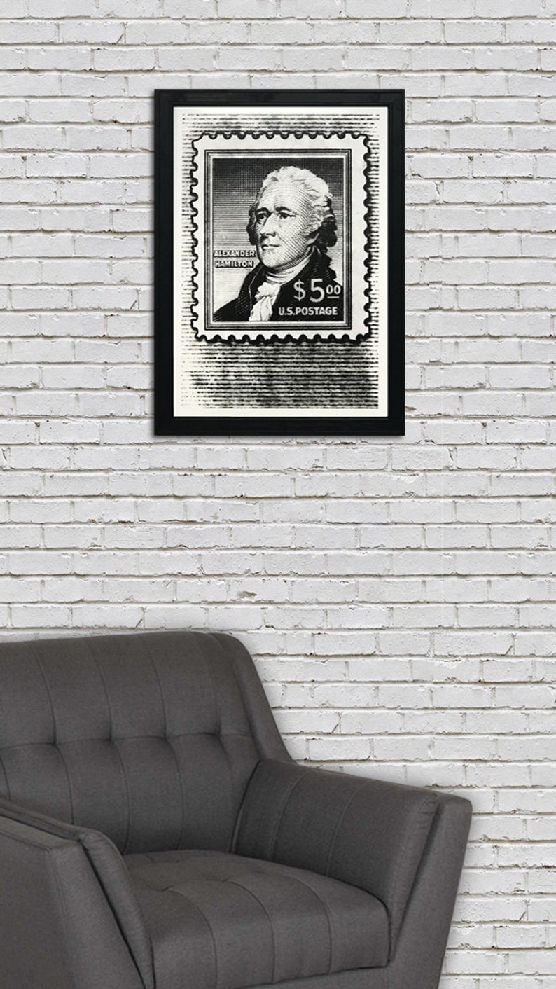 May include: Black and white framed print of a vintage postage stamp featuring a portrait of Alexander Hamilton with the text "ALEXANDER HAMILTON $5.00 U.S. POSTAGE".