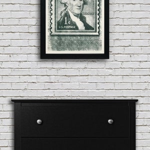 May include: A framed black and white print of a vintage US postage stamp featuring George Washington. The stamp is green and has the text "1&cent; U.S. POSTAGE" and "WASHINGTON" printed on it.