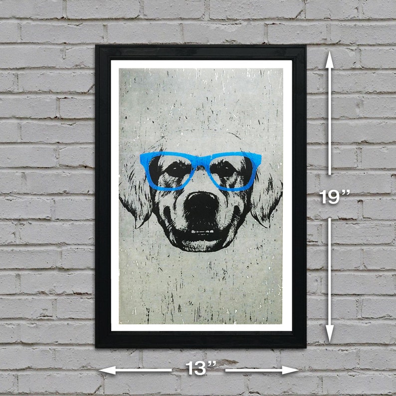 May include: A black framed print of a dog wearing blue glasses. The dog is a golden retriever with a white background. The print measures 13 inches wide by 19 inches tall.