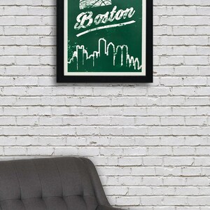 May include: A framed print with a green background and white text that says "Boston" with a basketball graphic above the text. The print also features a white silhouette of the Boston skyline.