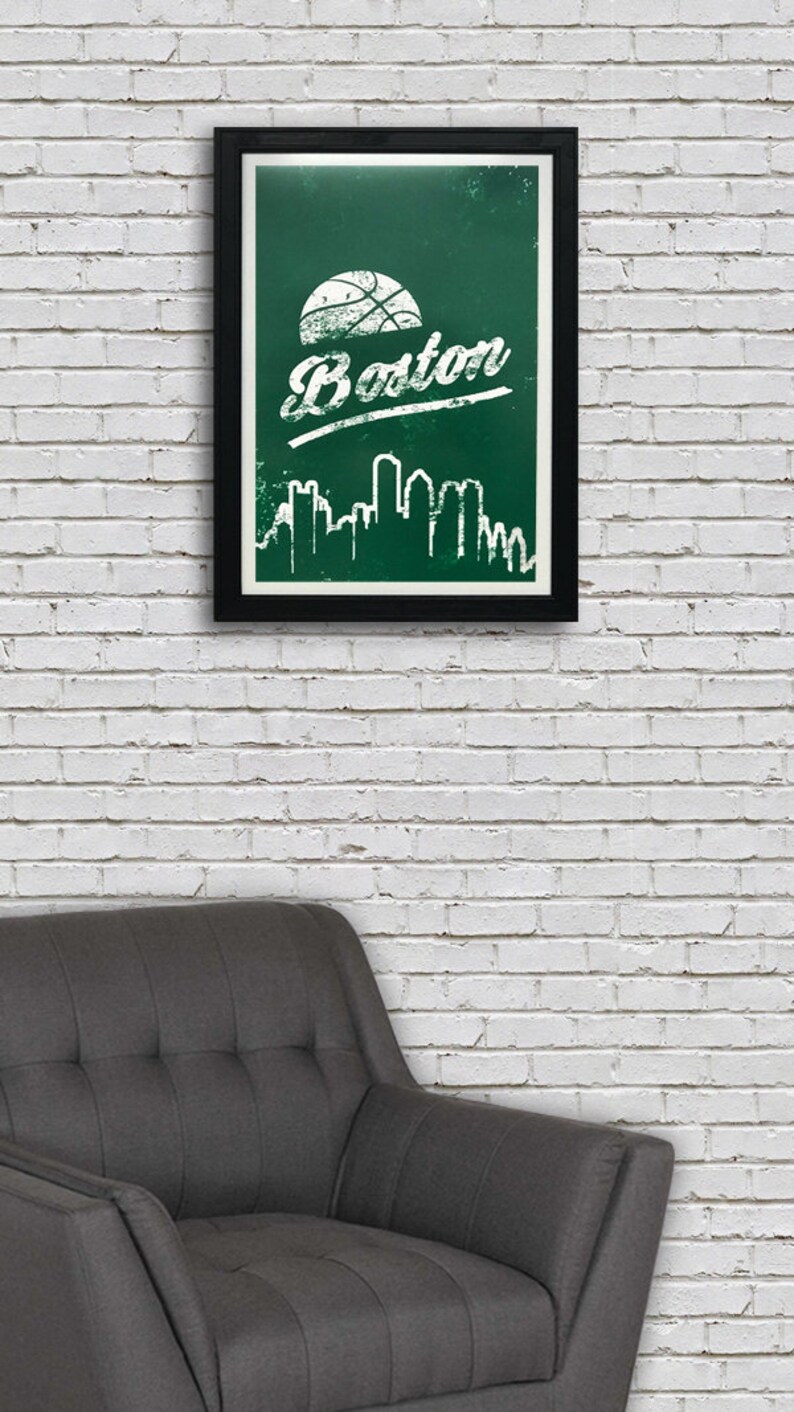 May include: A framed print with a green background and white text that says "Boston" with a basketball graphic above the text. The print also features a white silhouette of the Boston skyline.