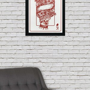May include: A framed print of a playing card featuring the King of Diamonds. The card is illustrated with a skull wearing a crown and a ruff. The card is in red and white.