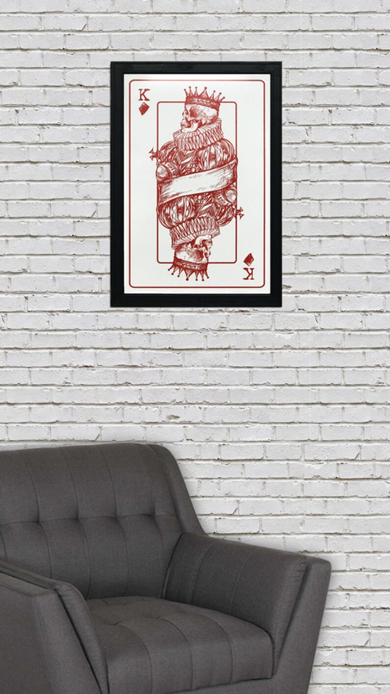 May include: A framed print of a playing card featuring the King of Diamonds. The card is illustrated with a skull wearing a crown and a ruff. The card is in red and white.