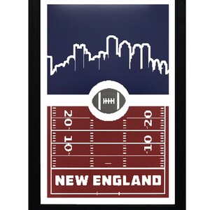 May include: A framed print with a white silhouette of the Boston skyline against a dark blue background. Below the skyline is a white football on a red and white football field with the text "NEW ENGLAND" in white.