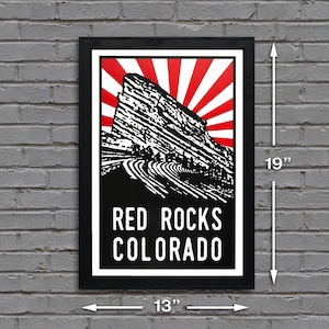 May include: Black and white poster with a red and white sunburst design. The poster features a stylized image of Red Rocks Amphitheatre in Colorado. The text "RED ROCKS COLORADO" is printed in white on a black background. The poster measures 13 inches wide by 19 inches tall.