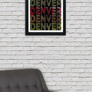 May include: A framed print with the word "DENVER" repeated five times in a retro, colorful font. The background is black with a subtle, glittery texture.