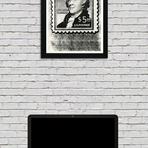 May include: Black and white framed print of a vintage postage stamp featuring a portrait of Alexander Hamilton with the text "Alexander Hamilton $5.00 U.S. Postage".
