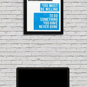 May include: A motivational quote in a black frame on a white brick wall. The quote reads: "If you want something you have never had, you must be willing to do something you have never done."